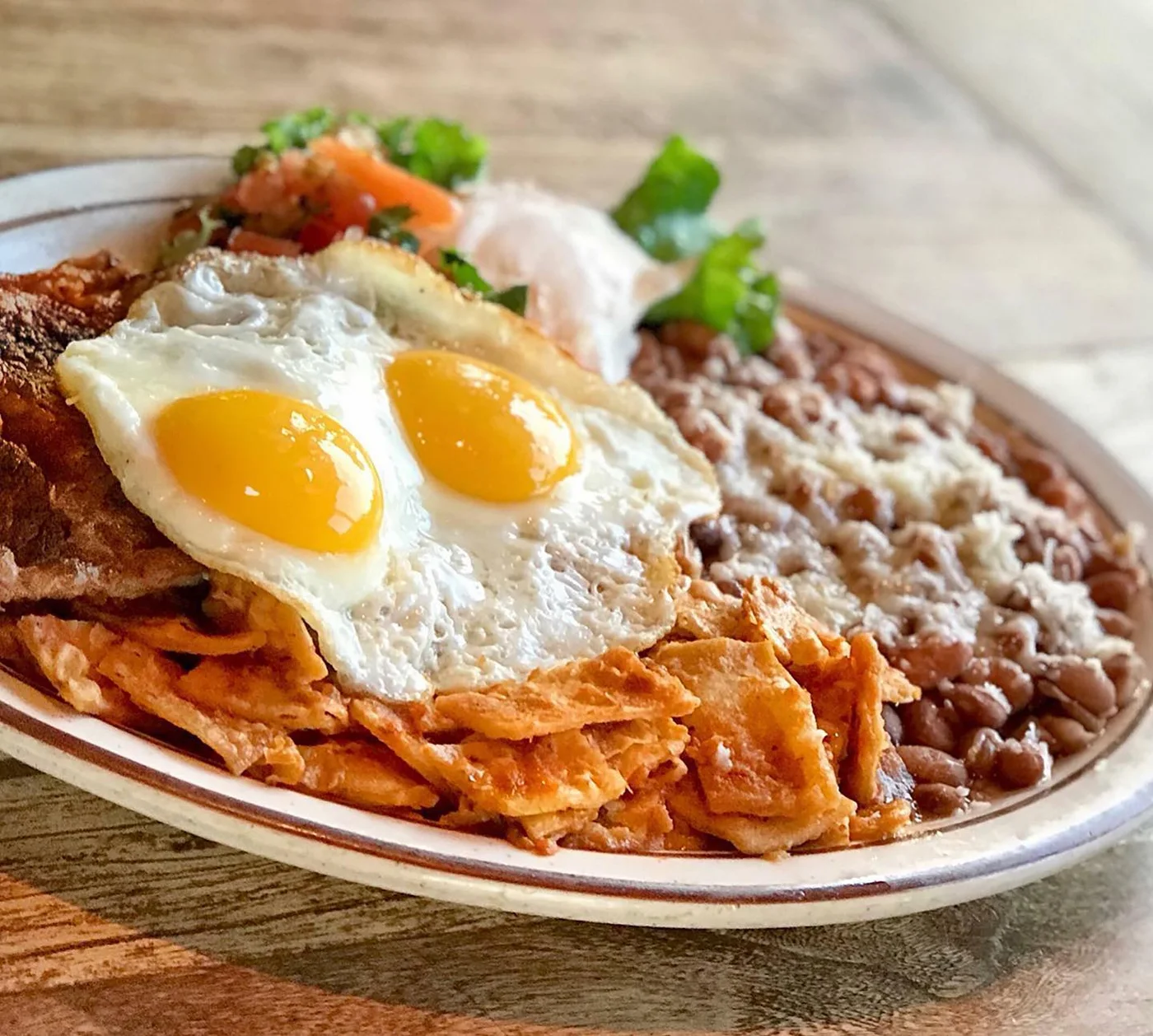 Chilaquiles topped with fried eggs, served with beans