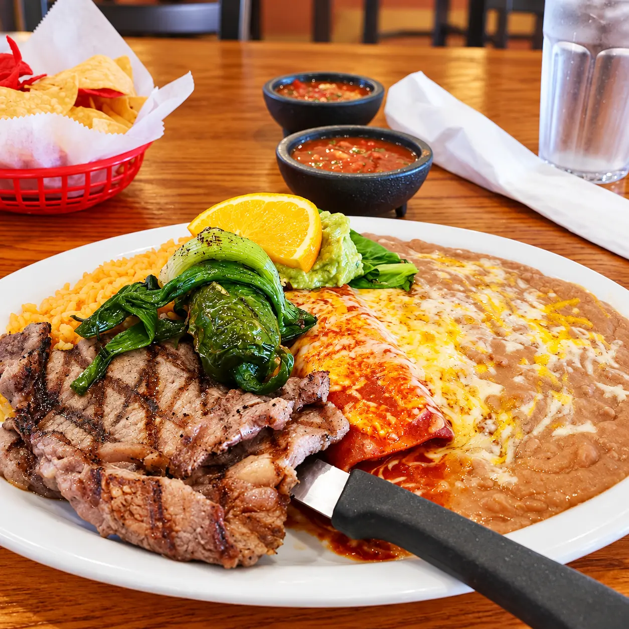 Grilled steak plate with roasted peppers, guacamole, rice, beans and a cheese enchilada