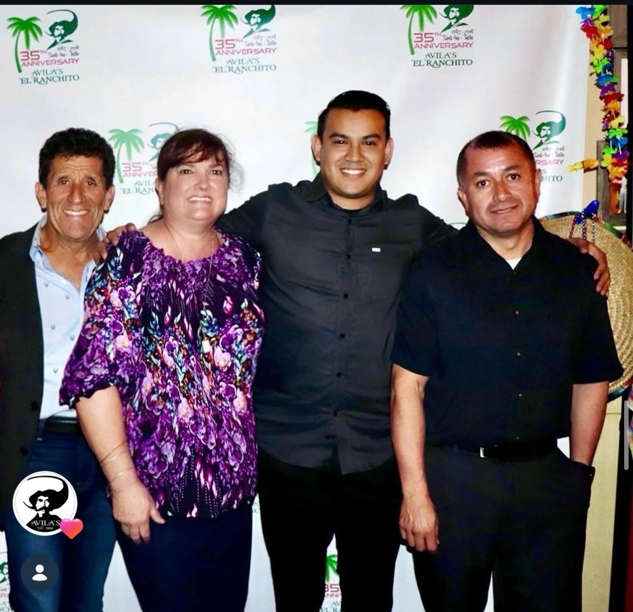 Four people posing together at an Avila’s El Ranchito 35th anniversary celebration.