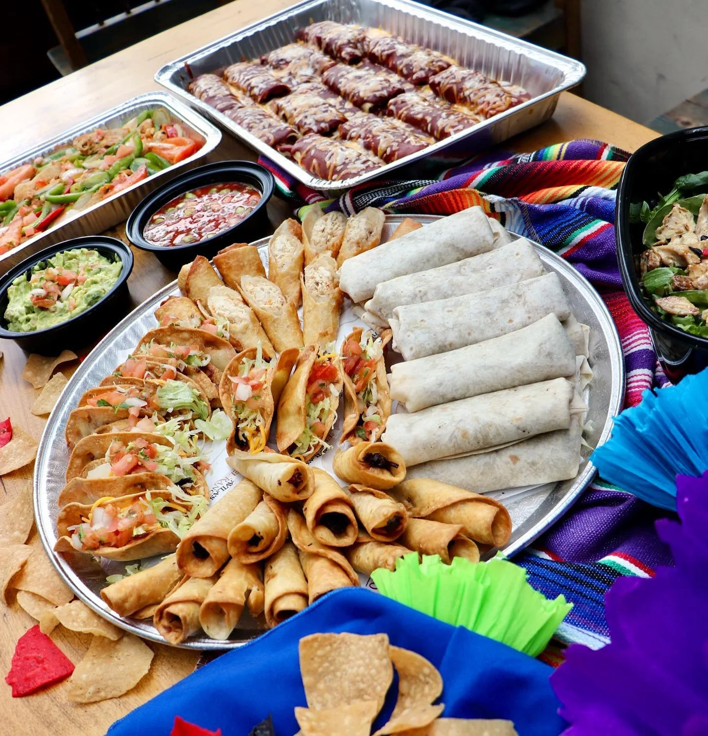 Party platter with tacos, flautas and burritos beside enchiladas and dips